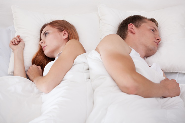 Couple lying in bed back to back